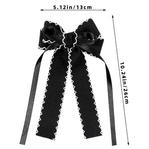 Detail of elegant black ribbon bow hair clip with white embroidered wavy edges