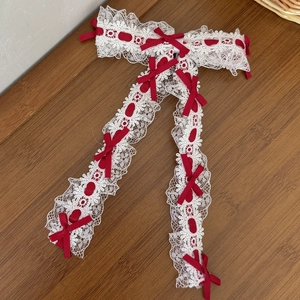 Vue détaillée d'un bandeau en dentelle blanche avec des nœuds rouges sur table en bois