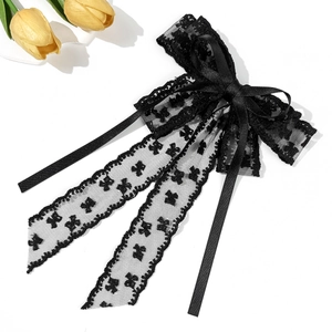 Detail of elegant black lace bow hair clip with intricate patterns and silk ribbons