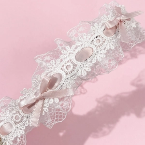 Détail d'une jarretière en dentelle blanche avec des rubans et des nœuds en satin rose