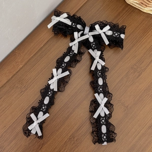 Détail d'une barrette en dentelle noire avec petits nœuds blancs en soie de style Lolita