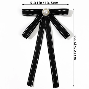 Detailed view of a black bow tie brooch with white stitching and a pearl center