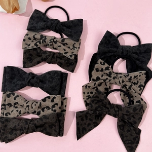 Set of retro leopard print bow hair scrunchies in various shades on pink background