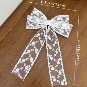 Detailed close-up of a white floral lace bow hair clip with elegant long streamers