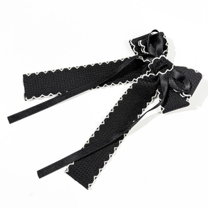 Close-up of black satin bow hair clip with elegant white contrast stitching details