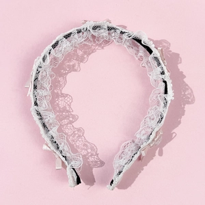 Détail d'un serre-tête Lolita avec dentelle plissée blanche et nœuds en ruban rose