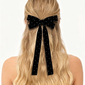 Detail of elegant black velvet bow hair clip with sparkling rhinestones on long ribbons