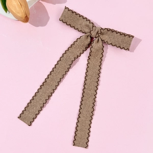 Detailed close-up of brown bow hair clip with twill texture and zigzag stitching