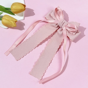 Pink waffle texture and satin ribbon bow clip displayed with flowers on a soft pink surface