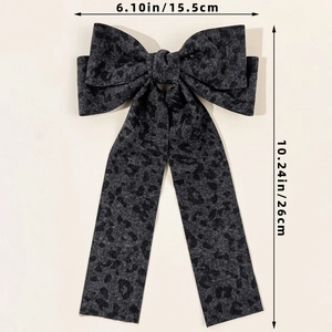 Detail of dark grey leopard print bow hair clip showing size dimensions 15.5cm and 26cm