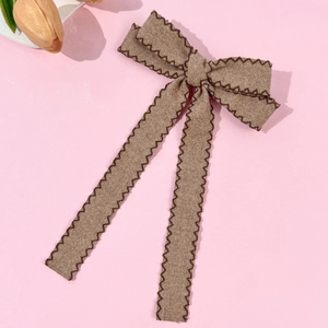Elegant brown wool bow hair clip with long ribbons and decorative stitching detail
