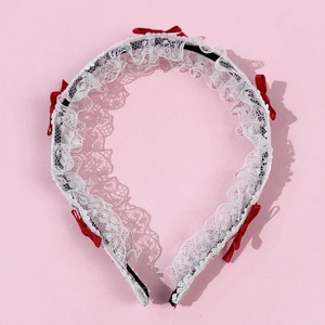 Détail d'un serre-tête en dentelle blanche orné de quatre nœuds en satin rouge
