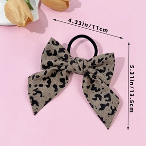Detail showing dimensions of leopard print bow scrunchie on soft pink background
