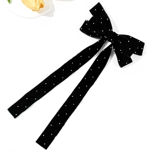 Detailed macro view of black velvet bow hair clip with sparkling rhinestones and long ribbons
