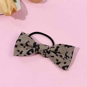 Detailed macro view of a vintage leopard print bow hair tie with grey textured fabric