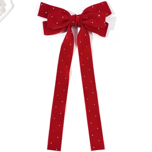 Close-up of red velvet bow hair clip with luxury rhinestones and long ribbon tails