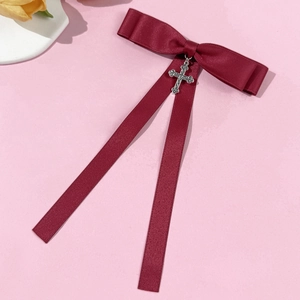 Close-up of wine red grosgrain ribbon bow with a silver hollowed cross pendant and long tassels