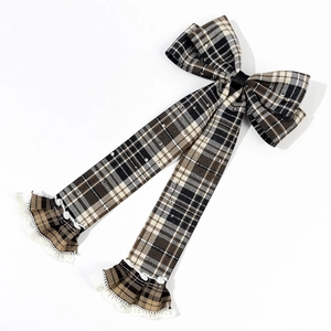 Detail view of plaid bow hair clip with elegant lace trimming and long ribbon tails