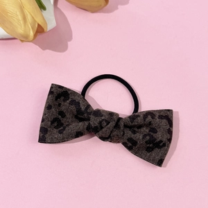 Detailed close-up of leopard print bow hair tie with elastic rope on pink background