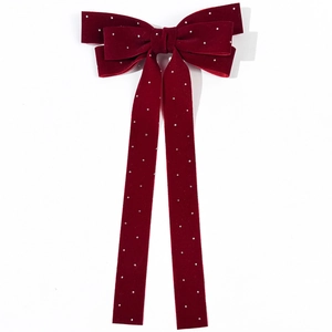 Close-up of wine red velvet bow hair clip with sparkling rhinestones and long streamers