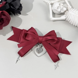 Detail van donkerrode gotische strik met hart-kruis hanger en stervormige bedels