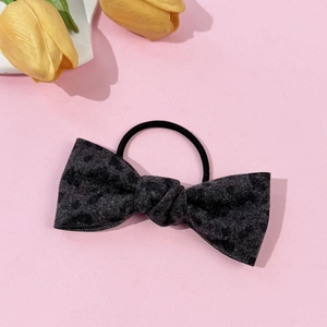 Detailed view of leopard print bow hair tie with elastic band on pink background