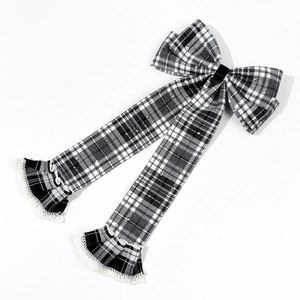 Detail of checkered bow hair clip with sequins, long ribbons, and delicate lace edges
