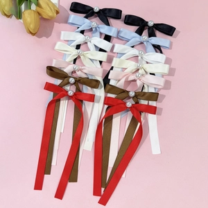 Vue à plat de nœuds à cheveux en satin coloré avec perles sur fond rose pastel