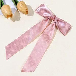 Pink polka dot bow hair clip with elegant long ribbons on a minimalist background