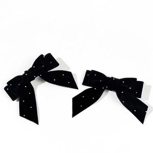 Detail of black velvet bow hair clips with sparkling rhinestones and metal duckbill clips