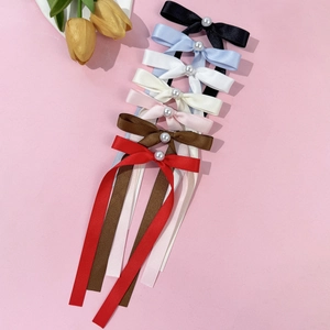 Détails de sept barrettes à nœuds en satin multicolores avec des perles centrales