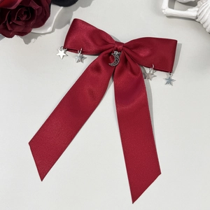 Gros plan sur un nœud en satin rouge foncé avec pendentifs lune et étoiles argentés