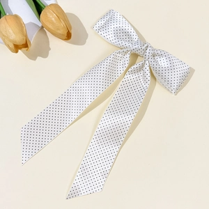 Close-up of elegant white satin bow hair clip with black polka dots and long ribbons
