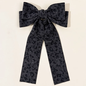 Close-up of leopard print bow hair clip with long ribbons in elegant vintage fabric