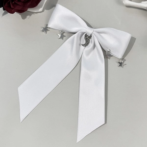 Vue détaillée d'un nœud en satin blanc avec des pendentifs en métal en forme d'étoile