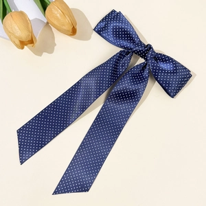 Close-up of a navy blue polka dot satin bow hair clip with long ribbons and tulips