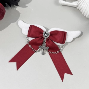 Detail of gothic bow hair clip with white wings, red satin, and silver cross pendant