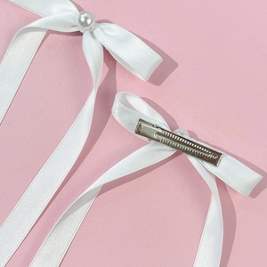 Pince à cheveux noeud en satin blanc avec perle et longs rubans sur fond rose