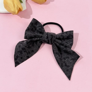 Detailed view of leopard print bow hair tie with elastic band on pink background