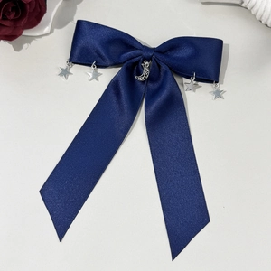 Détail d'un nœud papillon en satin bleu foncé avec pendentifs lune et étoiles