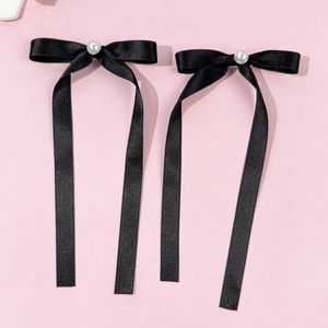 Détail de pinces à cheveux à nœuds en satin noir avec un centre en perle blanche brillante