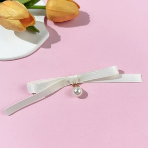 Détail d'un nœud en ruban blanc avec pendentif perle sur un fond rose pastel
