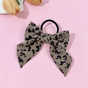 Detailed view of leopard print bow hair scrunchie with elastic band on pink surface