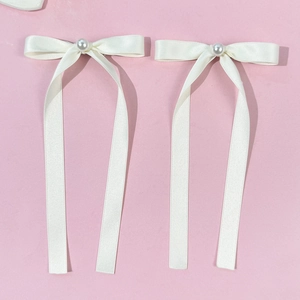 Détail des nœuds en ruban de soie crème style ballet avec perles sur fond rose