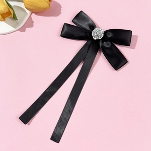 Close-up of black satin bow with silver rose decoration on a soft pink background