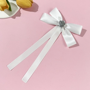 Detail of white satin bow brooch with silver rose center and long elegant ribbons