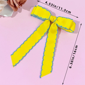 Détail de la barrette nœud jaune avec bords festonnés bleus et longs rubans, hauteur 16cm