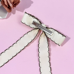 Pince à cheveux élégante avec nœud en ruban crème et bordure festonnée marron sur fond rose
