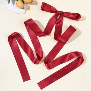 Detailed view of elegant deep red silk satin bow hair clip with long flowing ribbons
