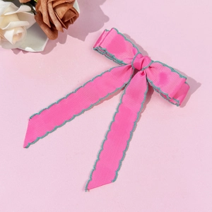 Détail du nœud rose en ruban côtelé avec broderie festonnée verte sur les bords